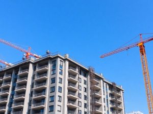 Clădire rezidențială modernă în construcție, cu macarale.